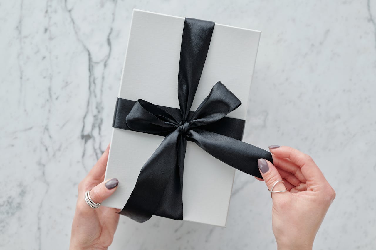 Services-02 A sleek white present tied with a black satin ribbon, providing a touch of luxury. Ideal for gift themes.