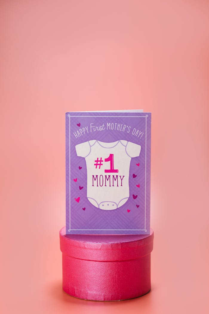 Purple greeting card for first Mother's Day on pink background.